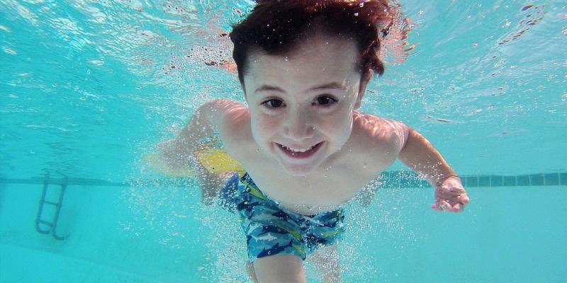 Child smiling underwater of a pool. 